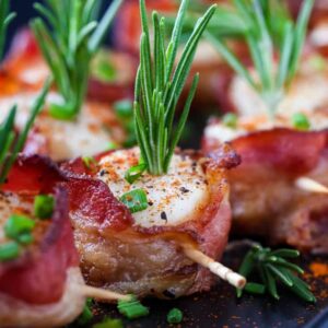 scallops wrapped with bacon and a rosemary garnish